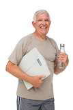 Cheerful senior man with water bottle and scales