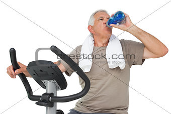 Senior man drinking water on stationary bike