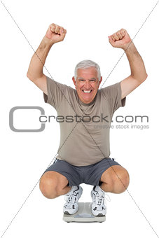 Portrait of a senior man cheering on weight scale