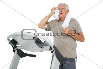 Tired senior man running on a treadmill