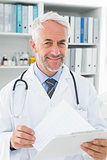 Portrait of a male doctor with reports in medical office