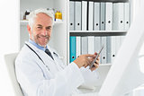 Smiling male doctor using digital tablet at medical office