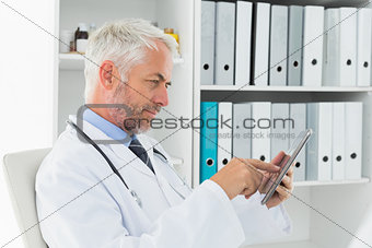 Concentrated doctor using digital tablet at medical office