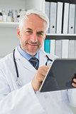 Male doctor using digital tablet at medical office