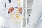 Mid section of doctor explaining the spine to patient