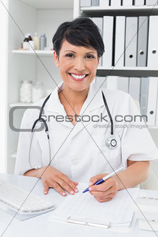 Portrait of a smiling doctor writing on clipboard