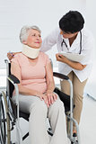Doctor talking to senior patient in wheelchair with cervical collar
