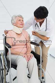 Doctor talking to senior patient in wheelchair with cervical collar