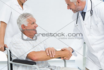 Smiling senior patient and doctor shaking hands