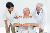 Happy senior patient with doctors sitting in wheelchair