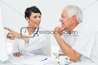 Doctor with male patient reading reports on computer