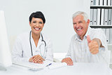 Happy senior patient gesturing thumbs up with doctor