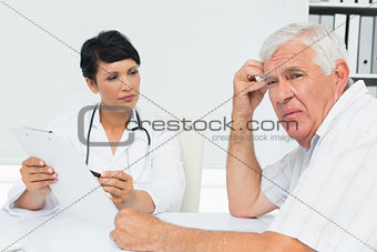 Doctor showing reports to worried senior patient