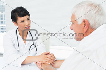 Female doctor holding senior patients hands