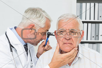 Close-up of a male doctor examining senior patient's ear