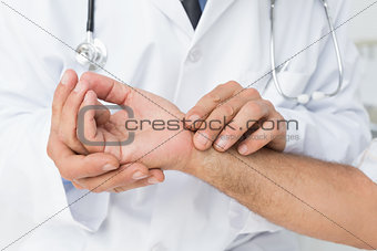 Mid section of a doctor taking a patients pulse