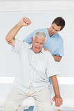 Mhysiotherapist assisting senior man to raise hand