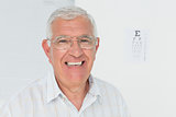 Portrait of a smiling senior man with eye chart in background