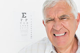 Portrait of a senior man with eye chart in background