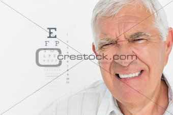 Portrait of a senior man with eye chart in background