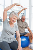 Senior couple doing stretching exercises on fitness balls