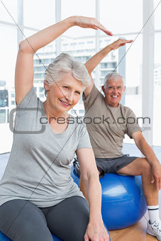 Senior couple doing stretching exercises on fitness balls