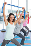 Class holding up exercise belts at yoga class