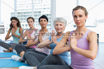 Class sitting with joined hands in a row at yoga class