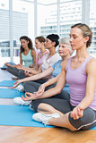 Women in lotus pose with eyes closed at fitness studio