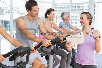 Trainer besides people working out at spinning class