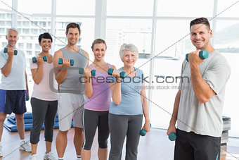 Class exercising with dumbbells in gym