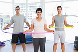 Fitness class holding hula hoops around waist in gym