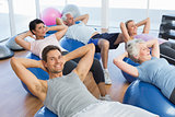 Smiling people stretching on exercise balls in gym
