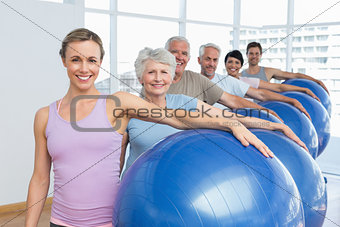 Portrait of sporty people carrying exercise balls in gym
