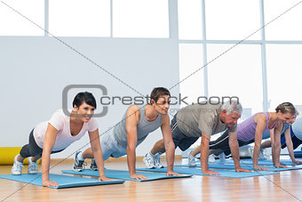 Group doing push ups in row at yoga class