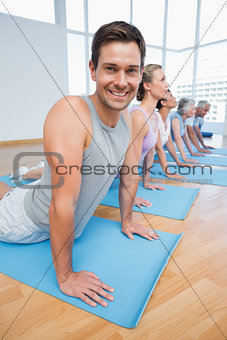 Froup doing cobra pose in row at yoga class
