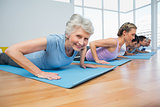 Group doing cobra pose in row at yoga class