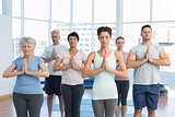 People with eyes closed and joined hands at fitness studio