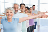 Portrait of fitness class stretching hands in row