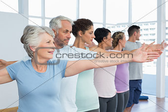 Class stretching hands in row at yoga class