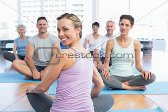 Sporty people sitting on exercise mats at fitness studio