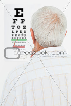 Rear view of a senior man looking at eye chart