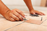 Worker hands placing spacers between ceramic floor tiles