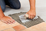 Worker hands spreading adhesive for ceramic floor tiles