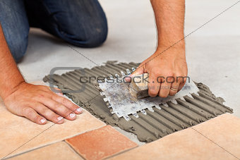 Worker hands spreading adhesive for ceramic floor tiles