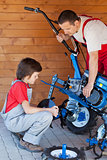 Boy helps his father mounting a cultivator machine