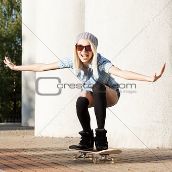 Beautiful blonde girl in short shorts with skateboard