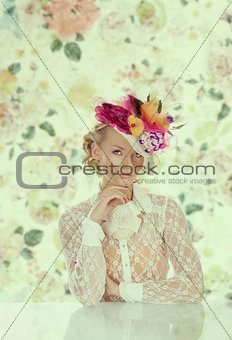 elegant girl behind table with floral hat and hand under the chi