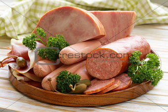 various kinds of sausages and smoked bacon on the wooden plate
