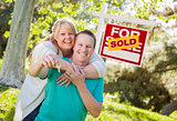 Couple In Front of Sold Real Estate Sign Holding Keys